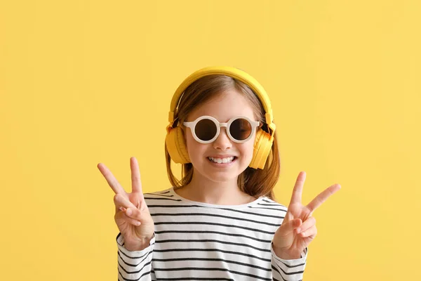 Kulaklıklı Küçük Kız Sarı Arka Planda Zafer Işareti Gösteriyor Yakın — Stok fotoğraf