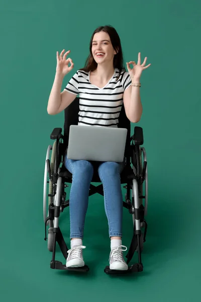 Молодая Женщина Ноутбуком Показывает Инвалидной Коляске Зеленом Фоне — стоковое фото