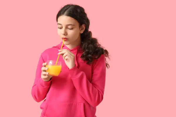 ピンクの背景にオレンジジュースを飲む十代の少女 — ストック写真