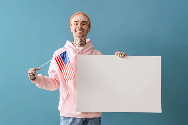 Young man with USA flag and blank poster on blue background
