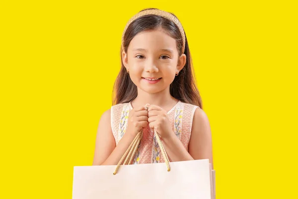 黄色の背景にショッピングバッグを持つかわいい少女 — ストック写真