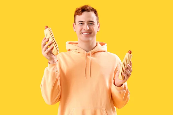 Junger Mann Mit Leckeren Hot Dogs Auf Gelbem Hintergrund — Stockfoto
