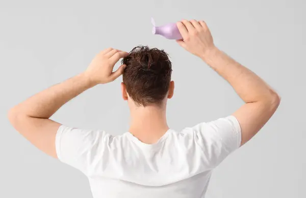 Jongeman Het Aanbrengen Van Shampoo Zijn Haar Tegen Lichte Achtergrond — Stockfoto