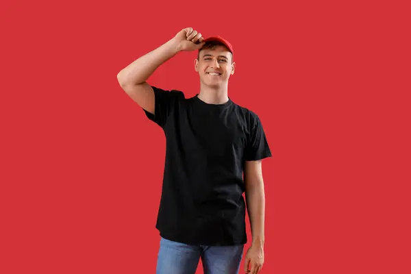 Kırmızı Arka Planda Siyah Tişörtlü Şapkalı Genç Adam — Stok fotoğraf