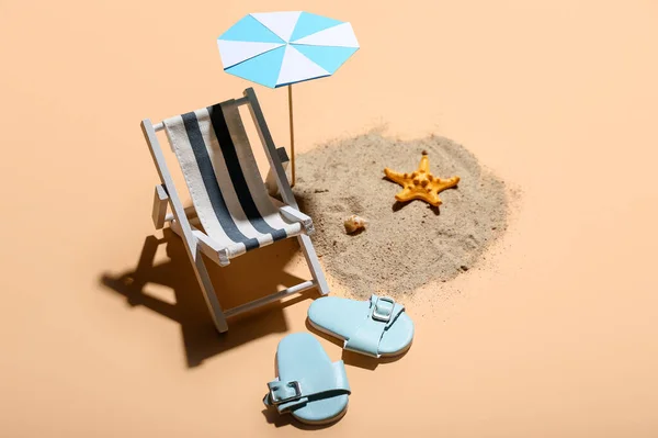 Creative summer composition with mini umbrella, deckchair and beach accessories on beige background