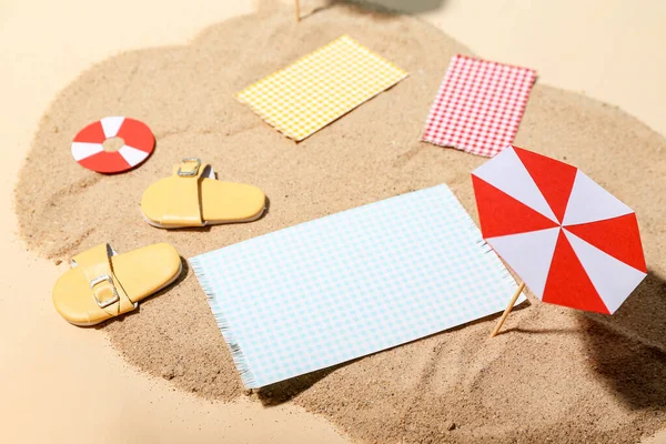 Creative summer composition with mini umbrella, beach accessories and sand on color background