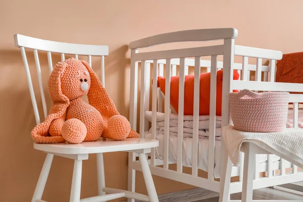 stock image Interior of children's room with crib and toys near beige wall