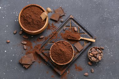 Siyah arka planda kakao tozu, çikolata ve fasulye dolu kaseler.