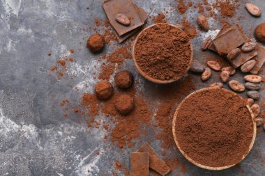 Siyah arka planda kakao tozu, şeker, fasulye ve çikolata dolu kaseler