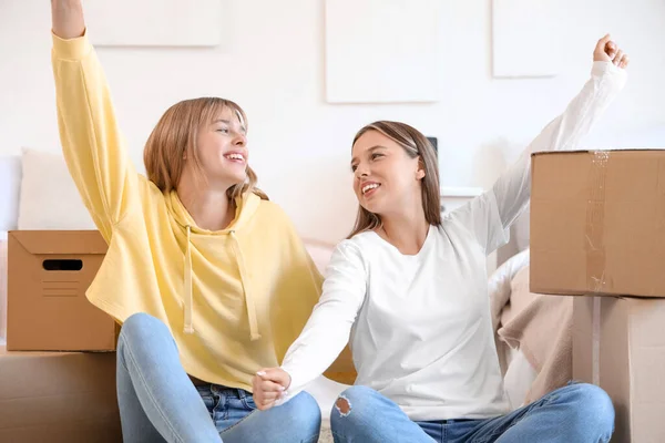 Female students with boxes in dorm room on moving day