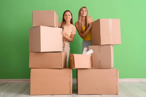 Female students with moving boxes near green wall in dorm room