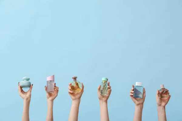 Manos Femeninas Sosteniendo Diferentes Perfumes Sobre Fondo Azul —  Fotos de Stock