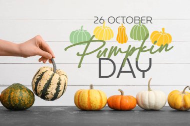 El ve pek çok farklı balkabağı, açık ahşap arka planda. Ulusal Balkabağı Günü için tebrik kartı