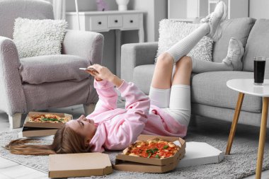 Evde cep telefonu kullanan lezzetli pizzalı genç bir kadın.