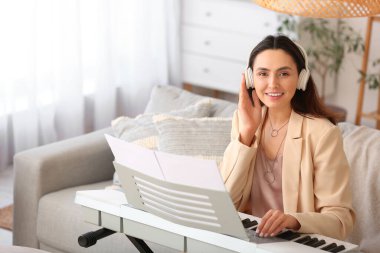 Genç bayan müzisyen evde sentezleyici çalıyor.