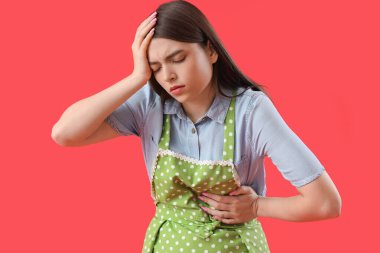 Genç ev hanımı kırmızı arka planda kalp krizi geçiriyor.