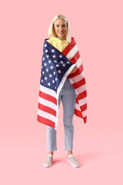 Pembe arka planda ABD bayrağı olan olgun bir kadın.