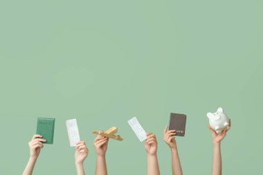 Pasaportları, biletleri, kumbarası ve yeşil arka planda tahta uçağı olan kadın eller. Seyahat kavramı