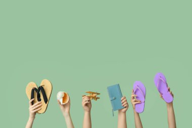 Parmak arası terlik, deniz kabuğu, cüzdan ve yeşil arka planda tahta uçak olan kadın eller. Seyahat kavramı