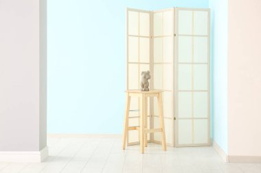 Renkli duvarın yanında katlanan ekran, tablo ve biblo