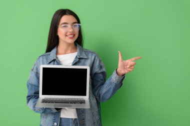 Yeşil arka planda dizüstü bilgisayarı olan mutlu bir kadın programcı.