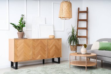 Ev bitkileri ve çekmecelerle aydınlık oturma odasının içinde.