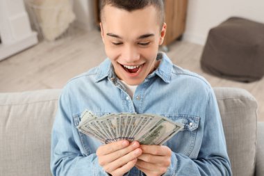 Memleketinde dolar banknotları olan mutlu genç bir adam.