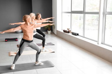 Sportif olgun kadınlar spor salonunda yoga yapıyor.