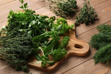 Tahta kesme tahtası ahşap arka planda farklı taze otlar, yakın plan