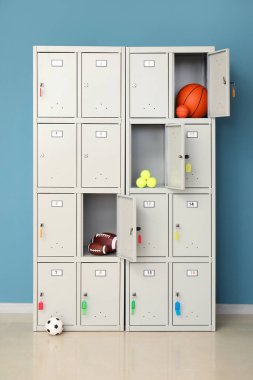Mavi duvarın yanında spor malzemeleri olan modern bir dolap.