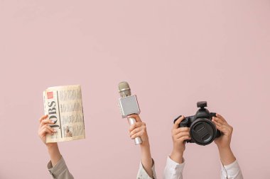 Arkaplanda gazete, mikrofon ve fotoğraf makinesi olan kadın eller