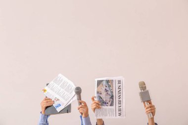 Arka planda gazete ve mikrofonları olan kadın eller.