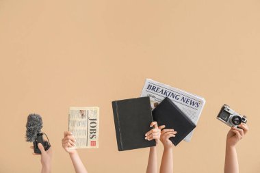 Renkli arka planda not defterleri, gazeteleri, mikrofonu ve fotoğraf makinesi olan kadın elleri
