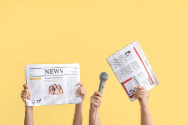 Arkaplanda gazete ve mikrofon bulunan kadın elleri