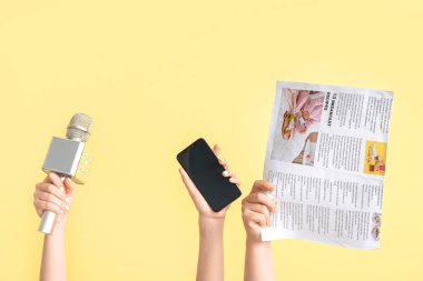 Arkaplanda mikrofon, cep telefonu ve gazete bulunan kadın eller