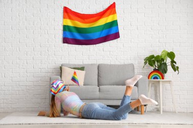Evde yerde yatan LGBT bayrağıyla genç bir kadın.