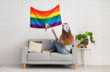 Kanepede LGBT bayrağı taşıyan genç bir kadın.