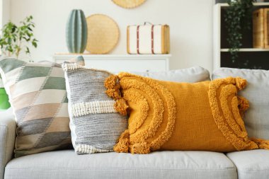 Şık oturma odasında yastıkları olan rahat gri kanepe, yakın plan.