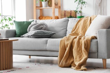 Aydınlık oturma odasının içinde şık gri kanepe ve ahşap sehpa var.