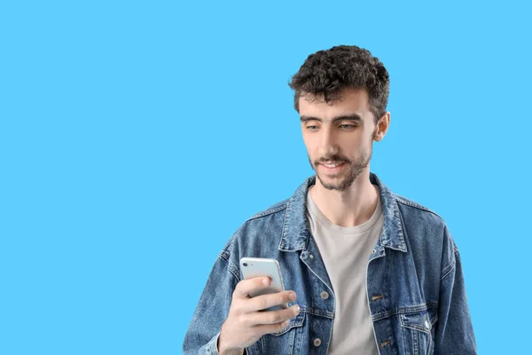 青い背景で携帯電話を使用してハンサムな若い男 — ストック写真