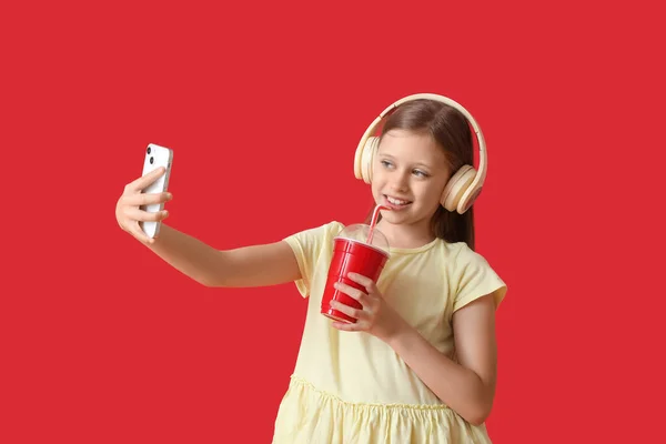 Маленька Дівчинка Навушниках Чашкою Содової Бере Селфі Червоному Тлі — стокове фото