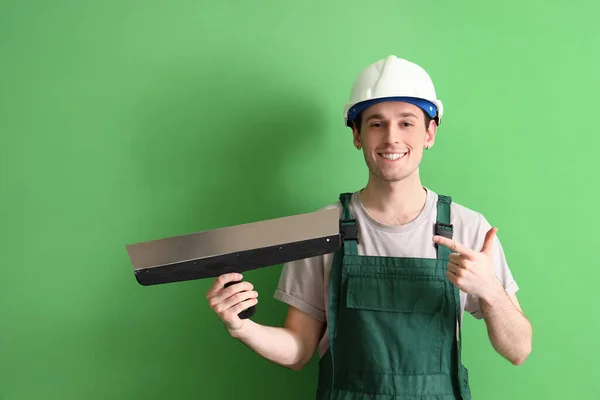 緑の背景にパティナイフを指す男性労働者 — ストック写真