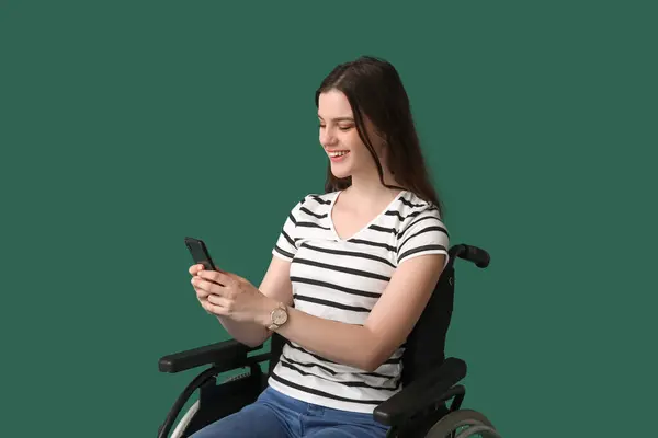 Молодая Женщина Мобильным Телефоном Инвалидной Коляске Зеленом Фоне — стоковое фото