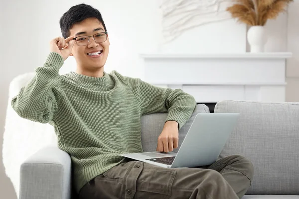 Young Asian man with laptop video chatting at home
