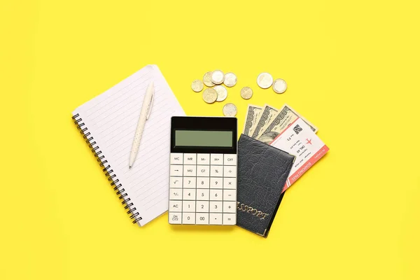 Calculator, passport, flight ticket and cash on yellow background