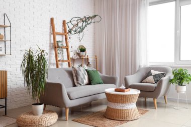 Rahat koltuğu, kanepesi ve masası olan modern oturma odasının içinde.