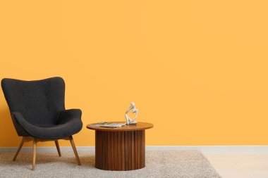 Dergileri, dekorasyonu ve renkli duvarın yanındaki rahat koltuğu olan ahşap masa.