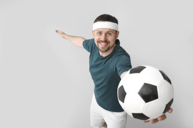 Arka planda futbol topu olan mutlu bir adam.