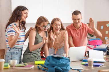 Dizüstü bilgisayarı olan bir grup öğrenci mutfakta sohbet ediyor.