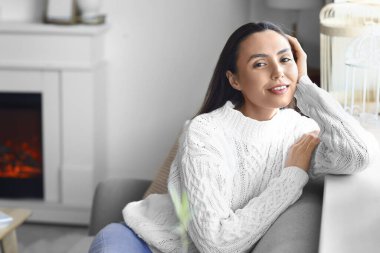 Evdeki kanepede oturan genç bir kadın.